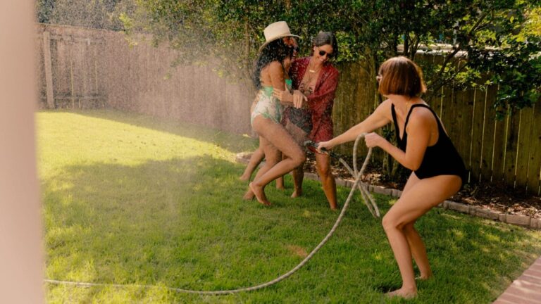 Women playing with water hose in the backyard
