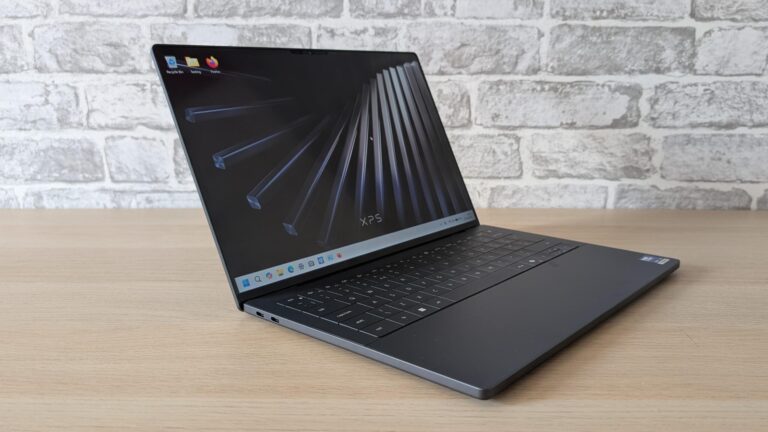 The new Dell XPS 14 laptop on a wooden table with its lid open and screen turned on