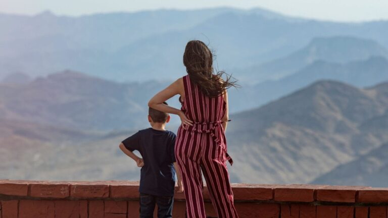 woman looking over mountain view with little boy