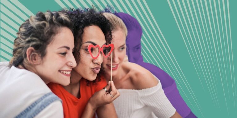 Close-up of mom with her two friends using a photo booth prop and taking a goofy selfie together